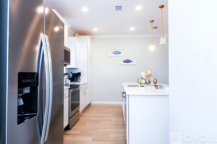 A modern kitchen with a stainless steel refrigerator and wooden flooring.