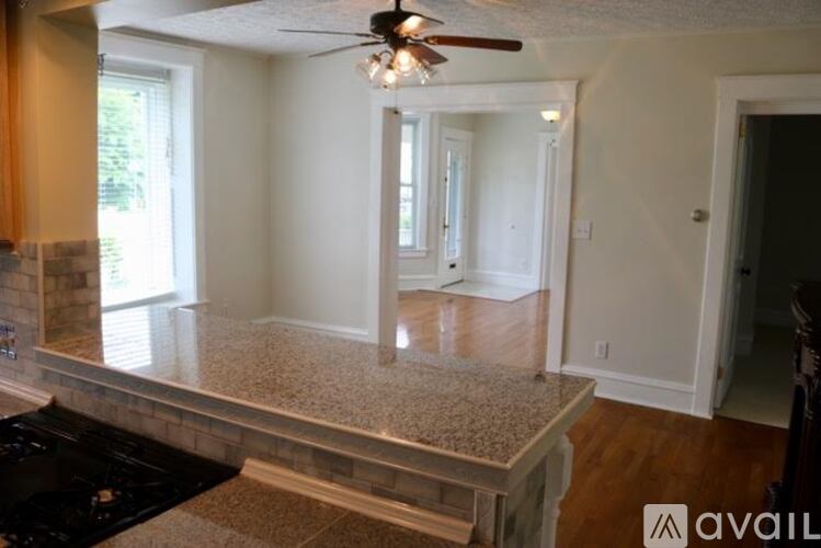 A kitchen with a black counter top and a ceiling fan.