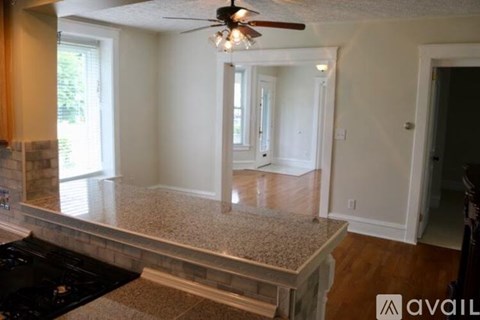 A kitchen with a black counter top and a ceiling fan.