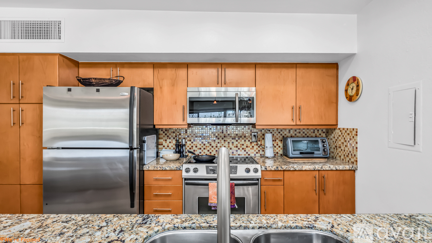 A kitchen with a stainless steel refrigerator and wooden cabinets.