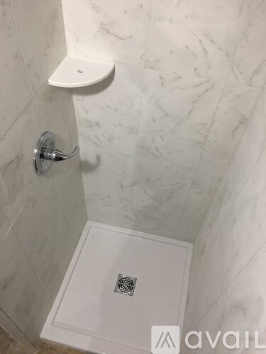 A white shower with a drain in the middle of the floor.