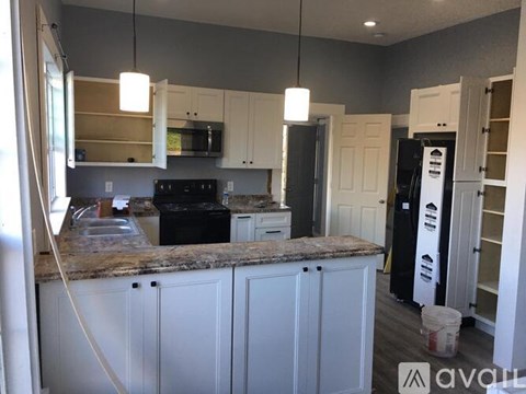 A kitchen with white cabinets and a granite countertop.