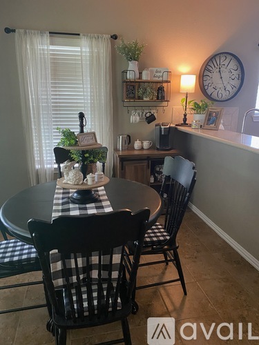 A dining room with a table set for two and a clock on the wall.