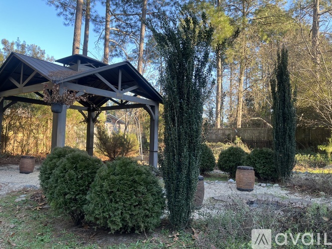 A gazebo surrounded by green shrubs and trees.
