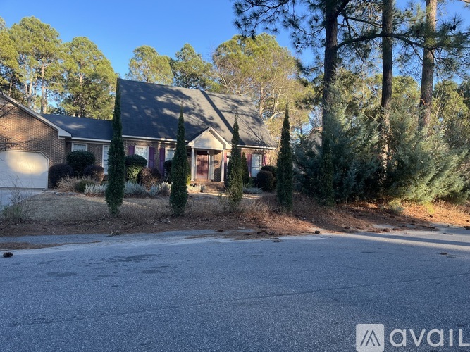 A house with a driveway in front of it surrounded by trees.