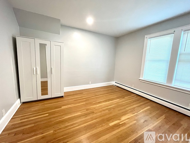 A room with wooden flooring and a window with blinds.