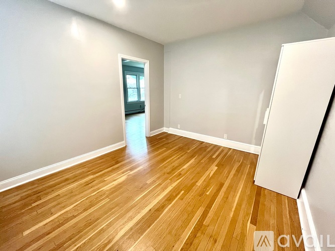 A room with wooden flooring and a doorway leading to another room.