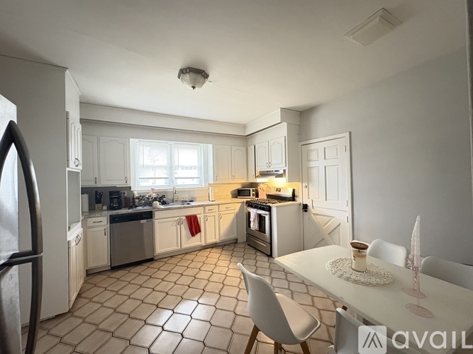 A kitchen with white cabinets and a tiled floor.