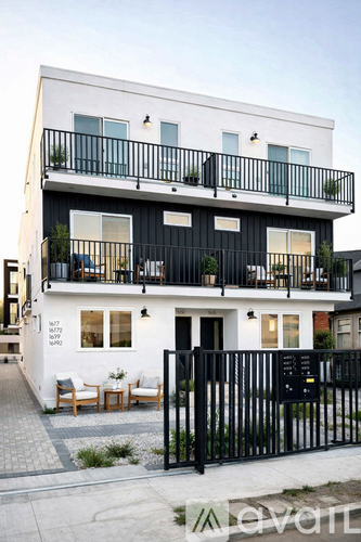 A white and black two story apartment building with balconies.