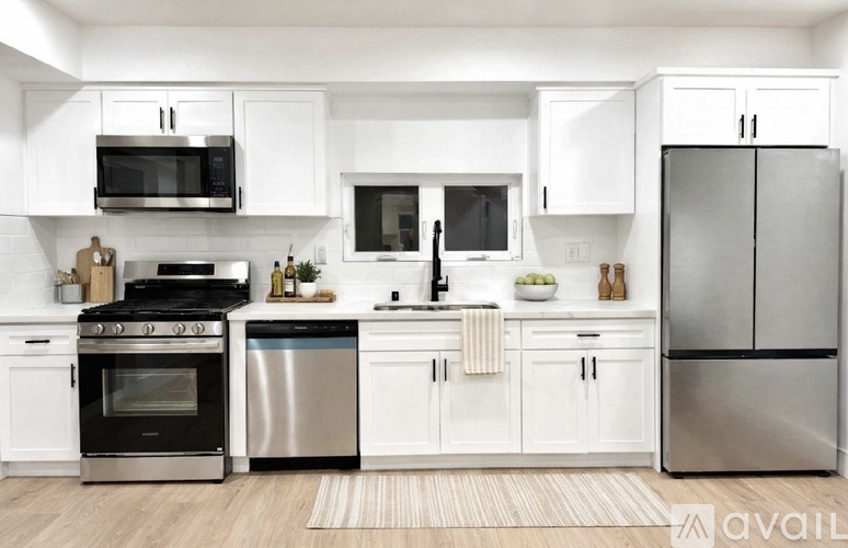 A modern kitchen with white cabinets and stainless steel appliances.
