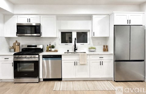 A modern kitchen with white cabinets and stainless steel appliances.