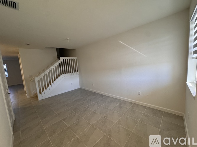 A spacious room with a staircase and tiled flooring.