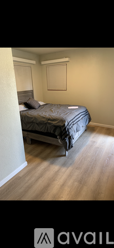 A bedroom with a bed and a wooden floor.