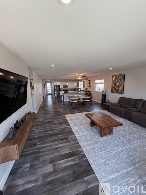 A spacious living room with a long wooden table and a grey carpet.