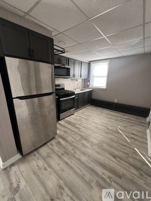 A kitchen with a stainless steel refrigerator and wooden floors.