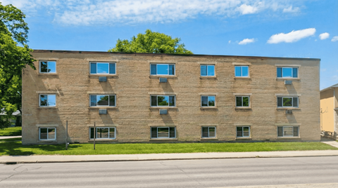 A large building with many windows is in front of a tree.