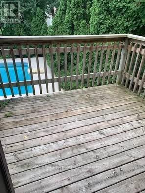 A wooden deck with a pool in the background.