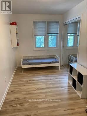 A bedroom with a bed, a window with blinds, and a wooden floor.