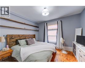 A bedroom with a bed, nightstand, and a window with curtains.