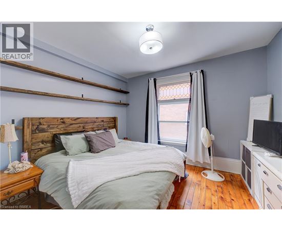 A bedroom with a bed, nightstand, and a window with curtains.