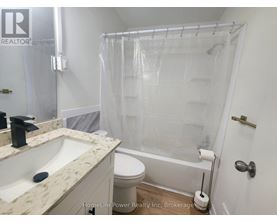 A white bathroom with a marble counter top and a glass shower enclosure.