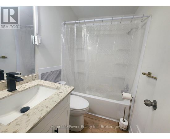 A white bathroom with a marble counter top and a glass shower enclosure.