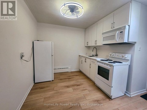 A kitchen with white appliances and cabinets.
