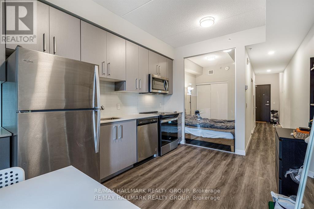 A kitchen with a refrigerator, microwave, oven and sink.