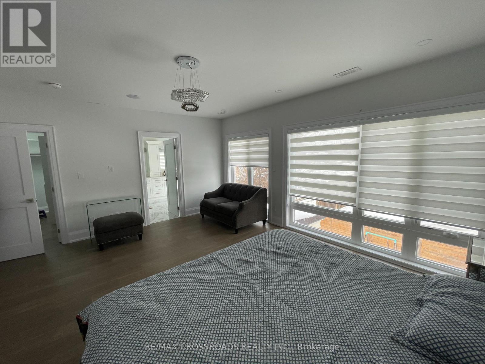 A bedroom with a large bed and a window with blinds.