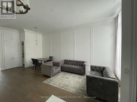 A living room with a grey couch and a dining table.