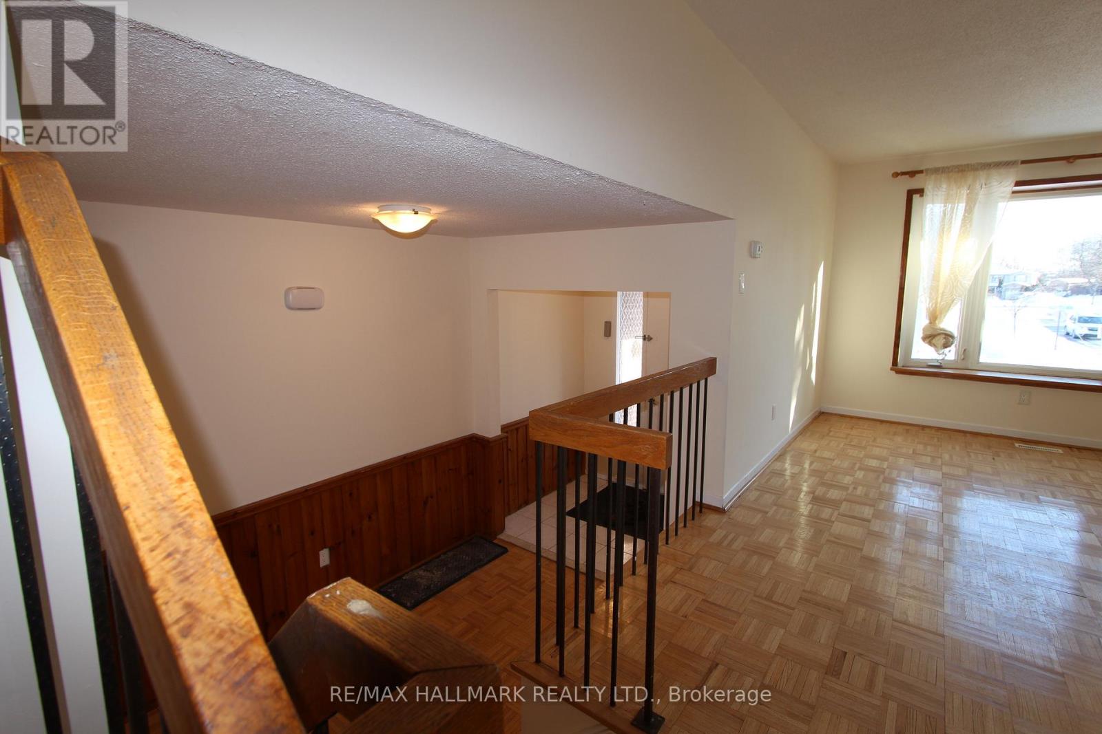 A room with wooden flooring and a window with white curtains.
