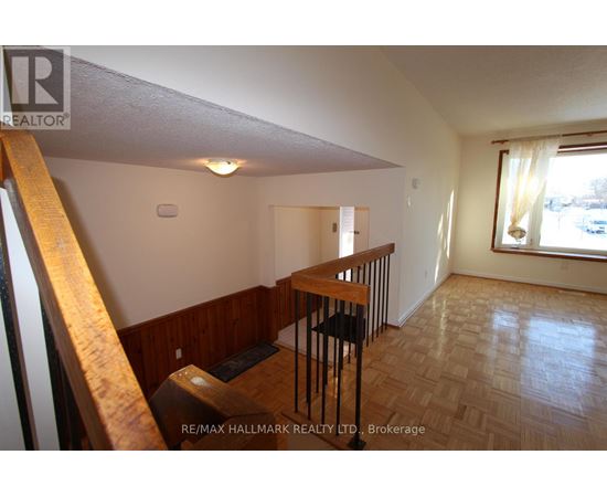 A room with wooden flooring and a window with white curtains.