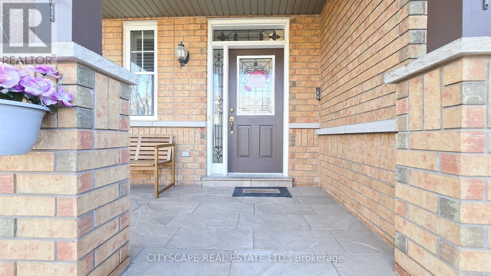 A front porch with a grey door and a grey planter with purple flowers.