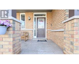 A front porch with a grey door and a grey planter with purple flowers.