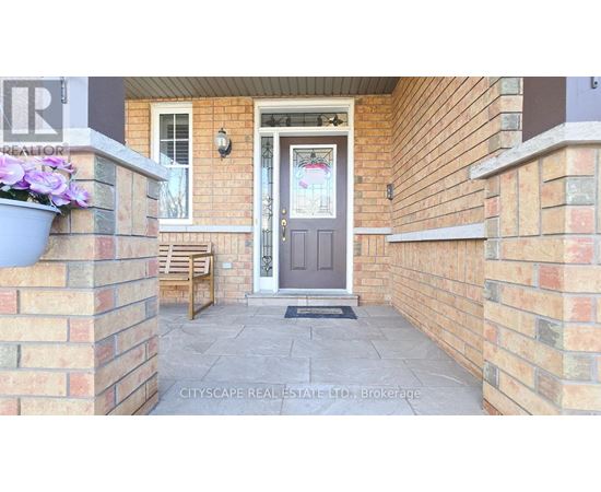 A front porch with a grey door and a grey planter with purple flowers.