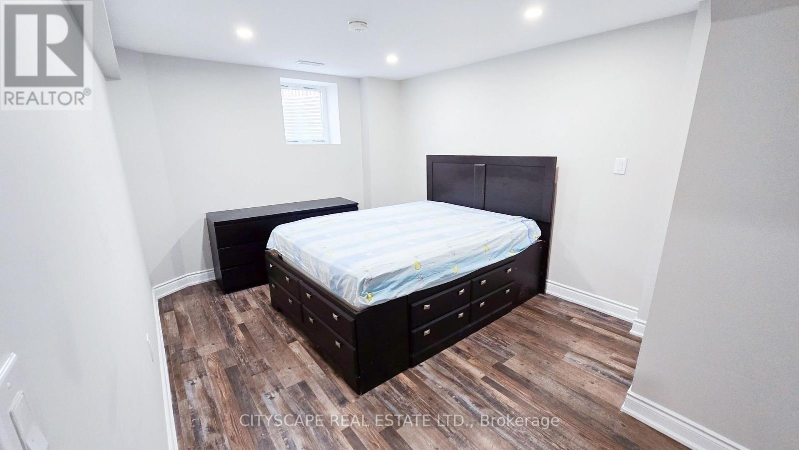 A bedroom with a bed and a wooden floor.