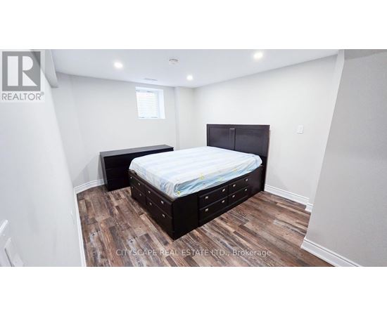 A bedroom with a bed and a wooden floor.