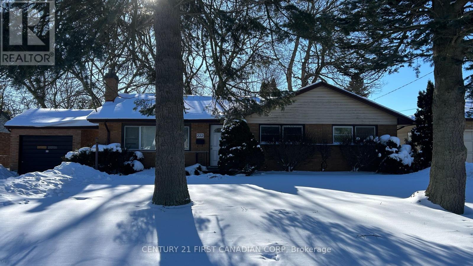 A house with a snow-covered front yard and a sign that says "REALTOR".