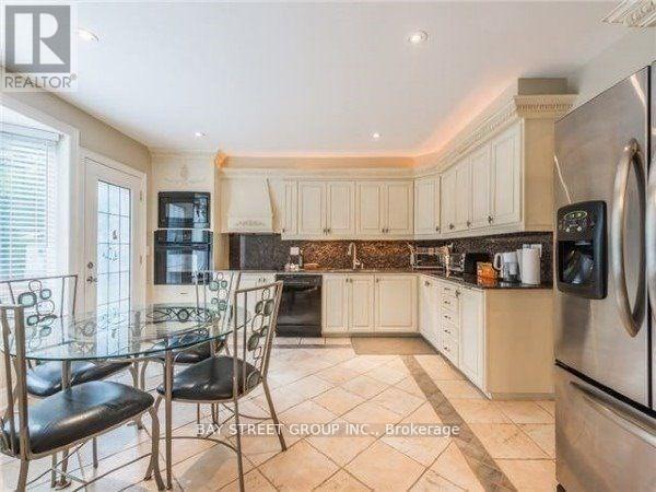 A kitchen with a glass table and chairs, and a refrigerator on the right.