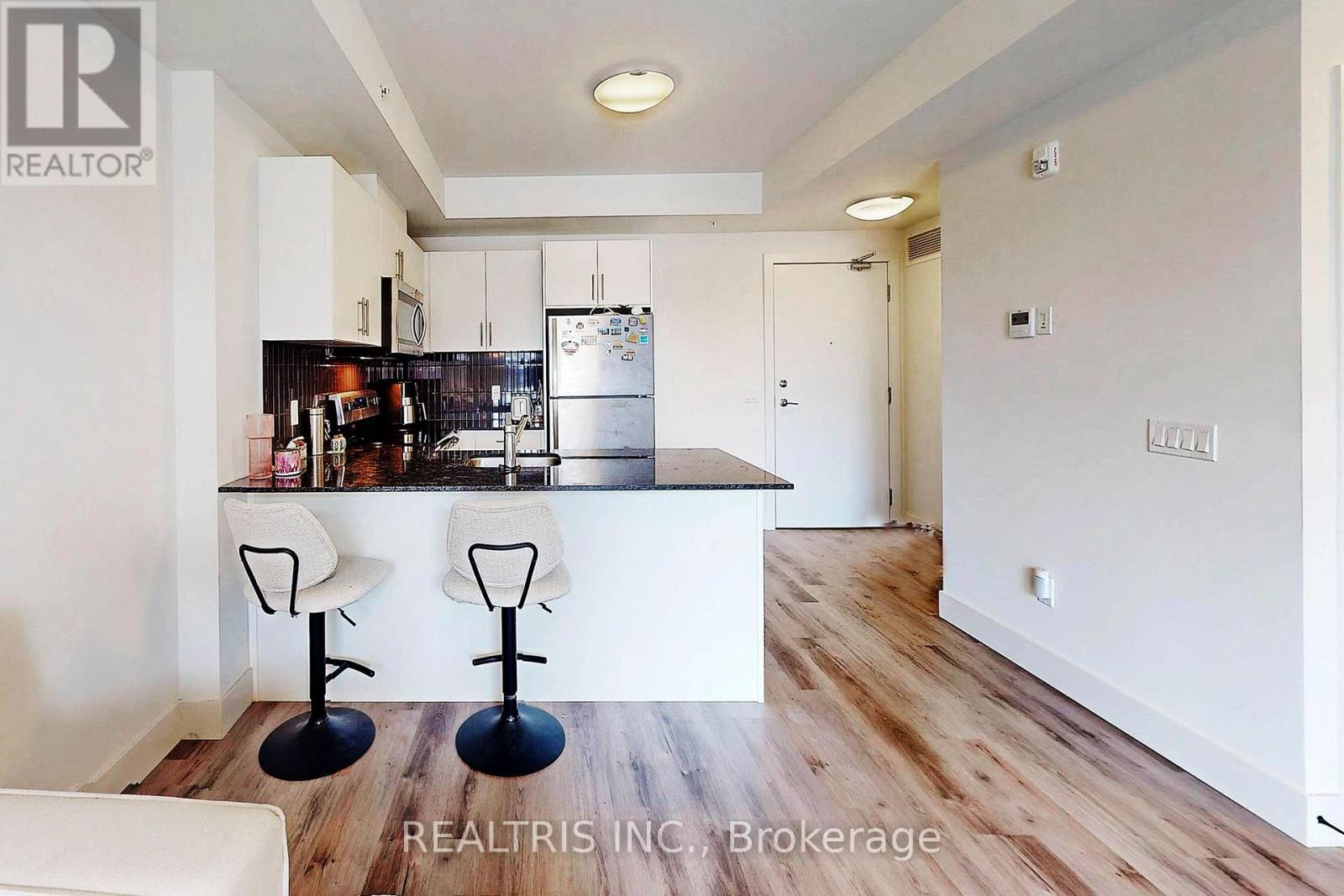 A modern kitchen with white cabinets and a bar area.