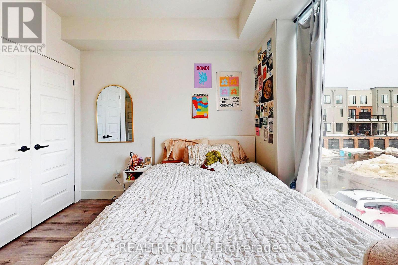 A bedroom with a large bed and a window overlooking a street.