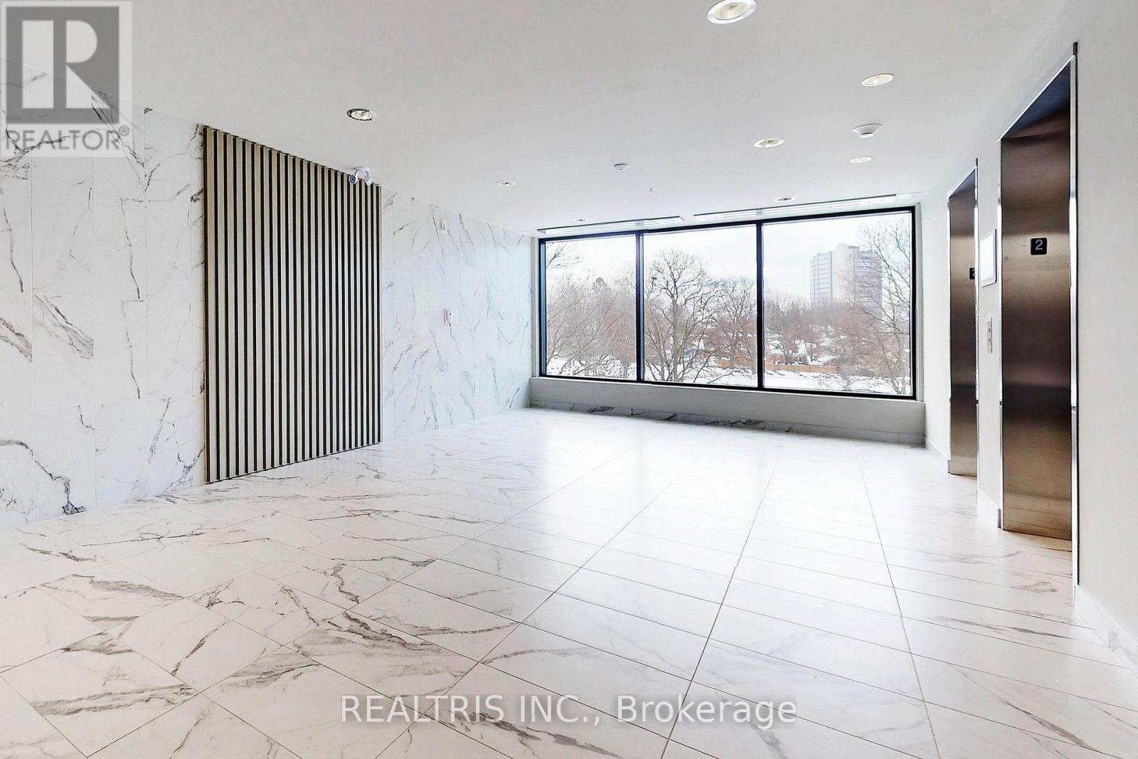 A spacious room with marble flooring and a large window overlooking a snowy landscape.