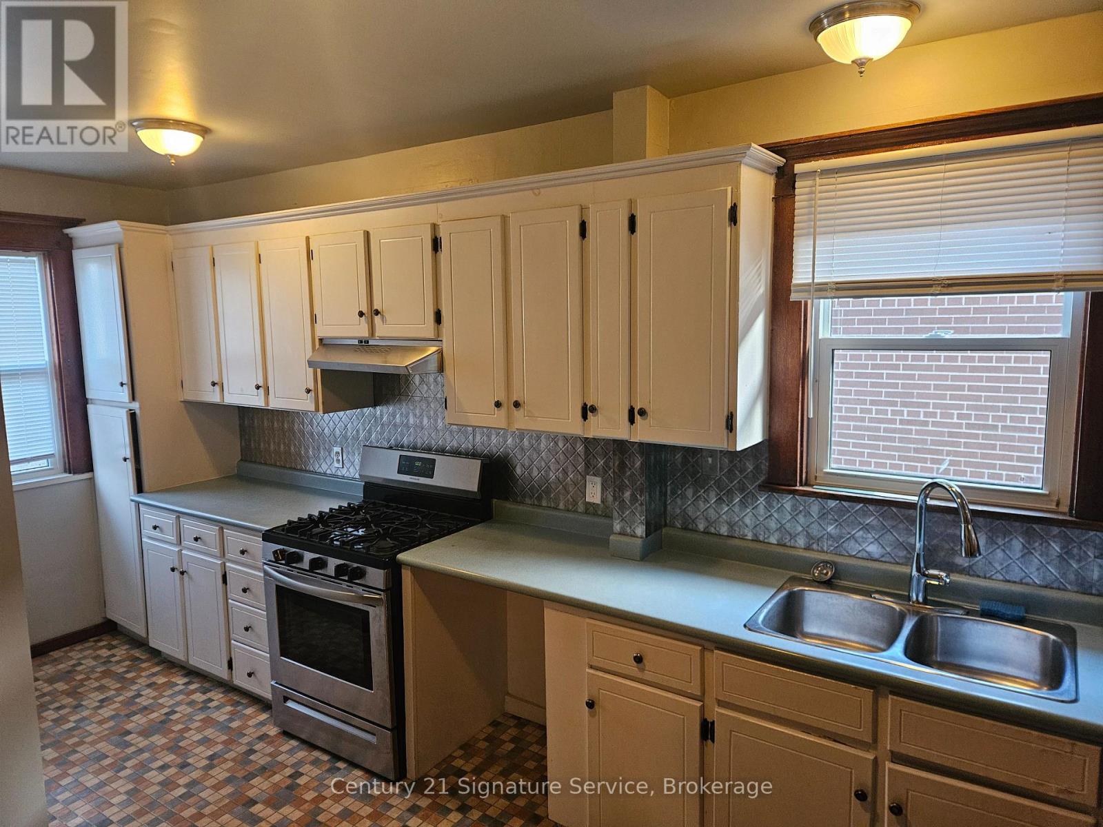 A kitchen with wooden cabinets and a tiled floor.