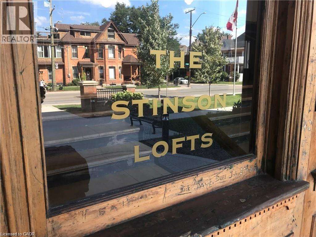 A window with a reflection of a building and the words "The Stinson Lofts" written on it.