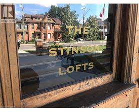 A window with a reflection of a building and the words "The Stinson Lofts" written on it.