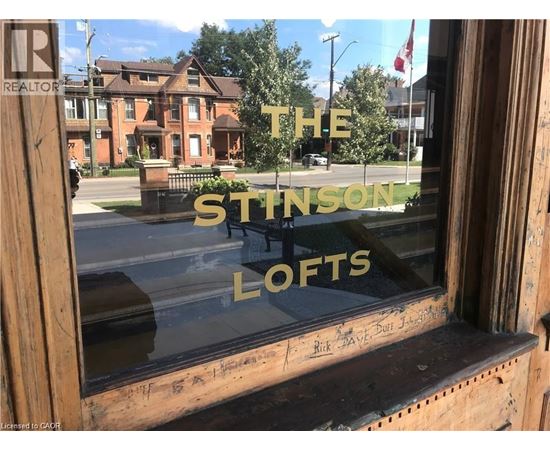 A window with a reflection of a building and the words "The Stinson Lofts" written on it.