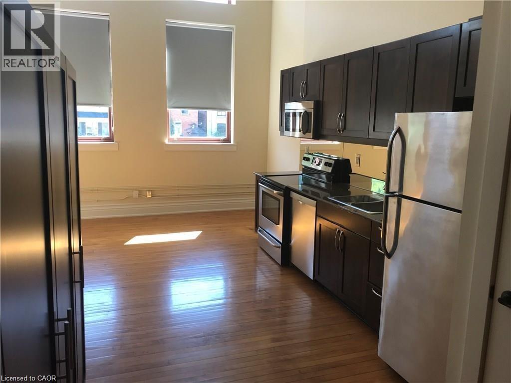 A kitchen with black cabinets and a refrigerator.