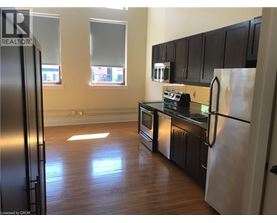 A kitchen with black cabinets and a refrigerator.