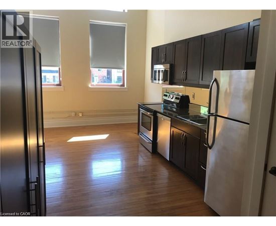A kitchen with black cabinets and a refrigerator.