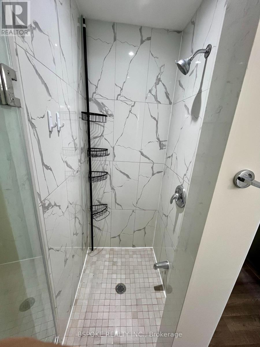 A bathroom with a marble wall and a walk-in shower.